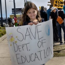 Sarah-Cummings-lleva-un-cartel-de-protesta-para-salvar-el-Departamento-de-Educación