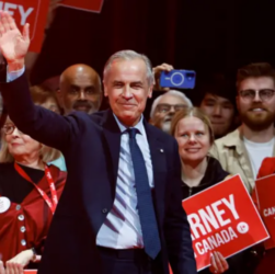 Mark Carney saluda al público con su mano derecha, detrás de él simpatizantes de su campaña. FOTO: REUTERS