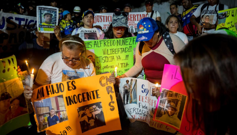 Migrantes venezolanos con carteles piden la libertad de sus familiares a Nayib Bukele. FOTO: EFE